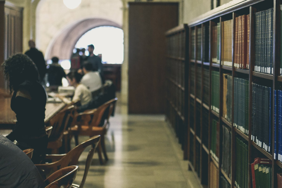 photo de bibliothèque abstraite avec un mur de livres d'un côté et des étudiants de l'autre